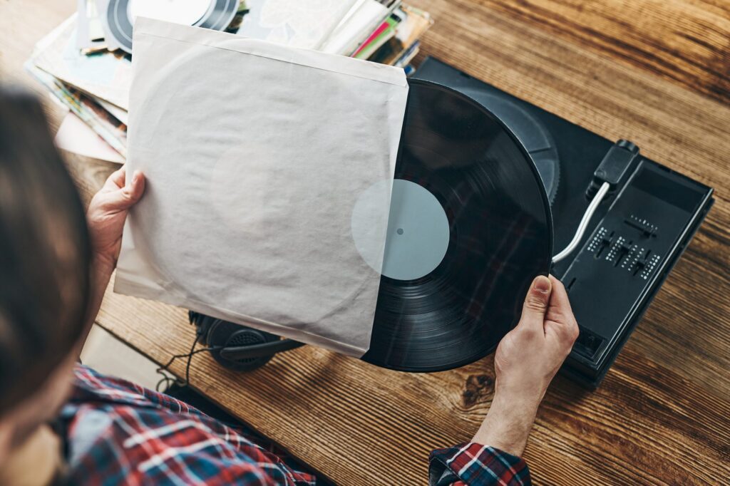 Person sliding a vinyl record out of its paper sleeve next to a turntable