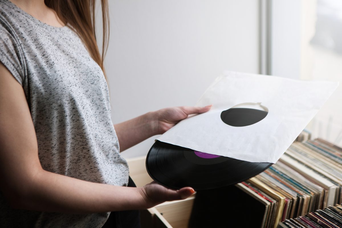 Hands holding a vinyl record partly out of its sleeve in a record shop