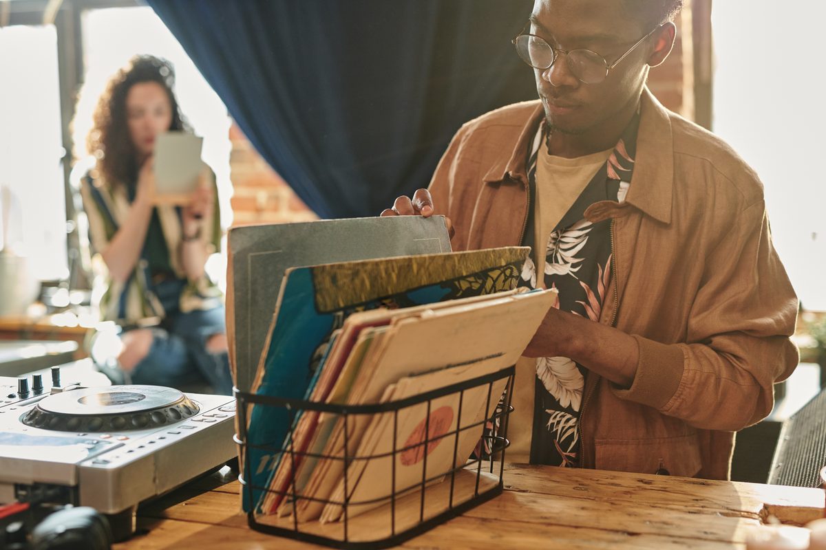 Man looking through vinyl records in a wire rack at home