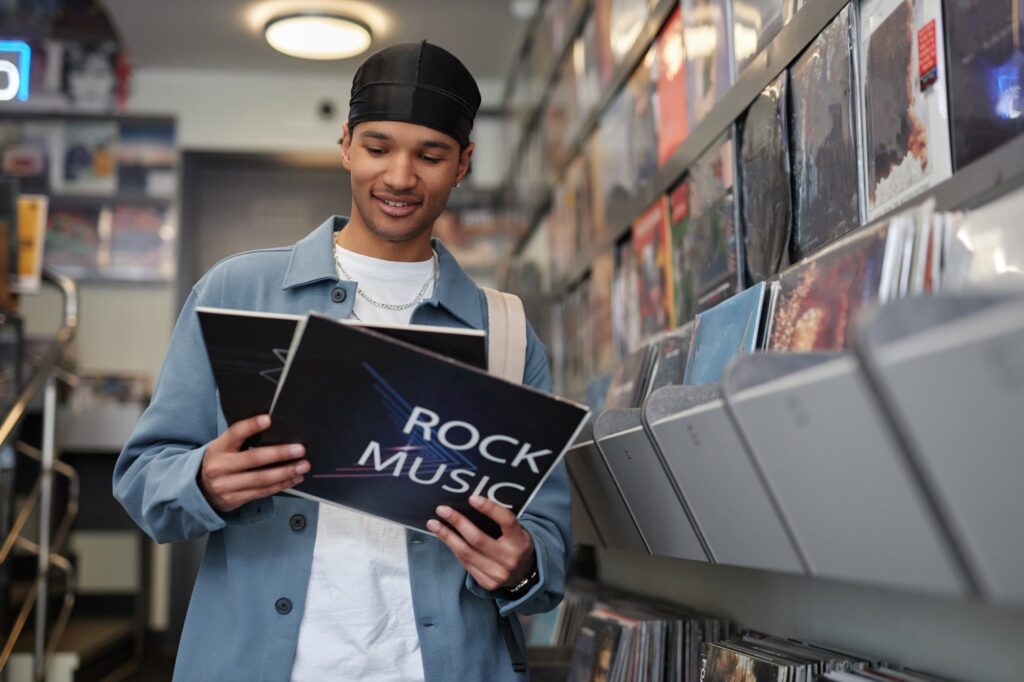 Smiling man holding a rock vinyl record sleeve in a record store