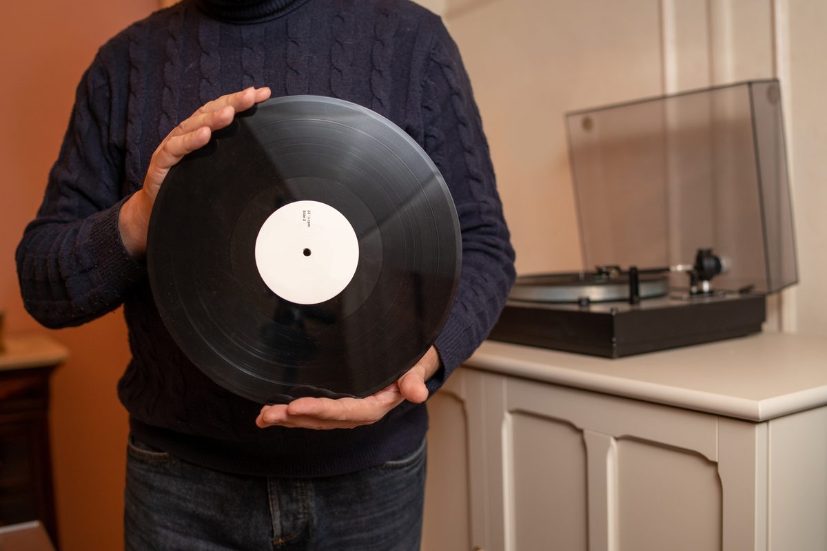 Man holding a vinyl record in front of a turntable
